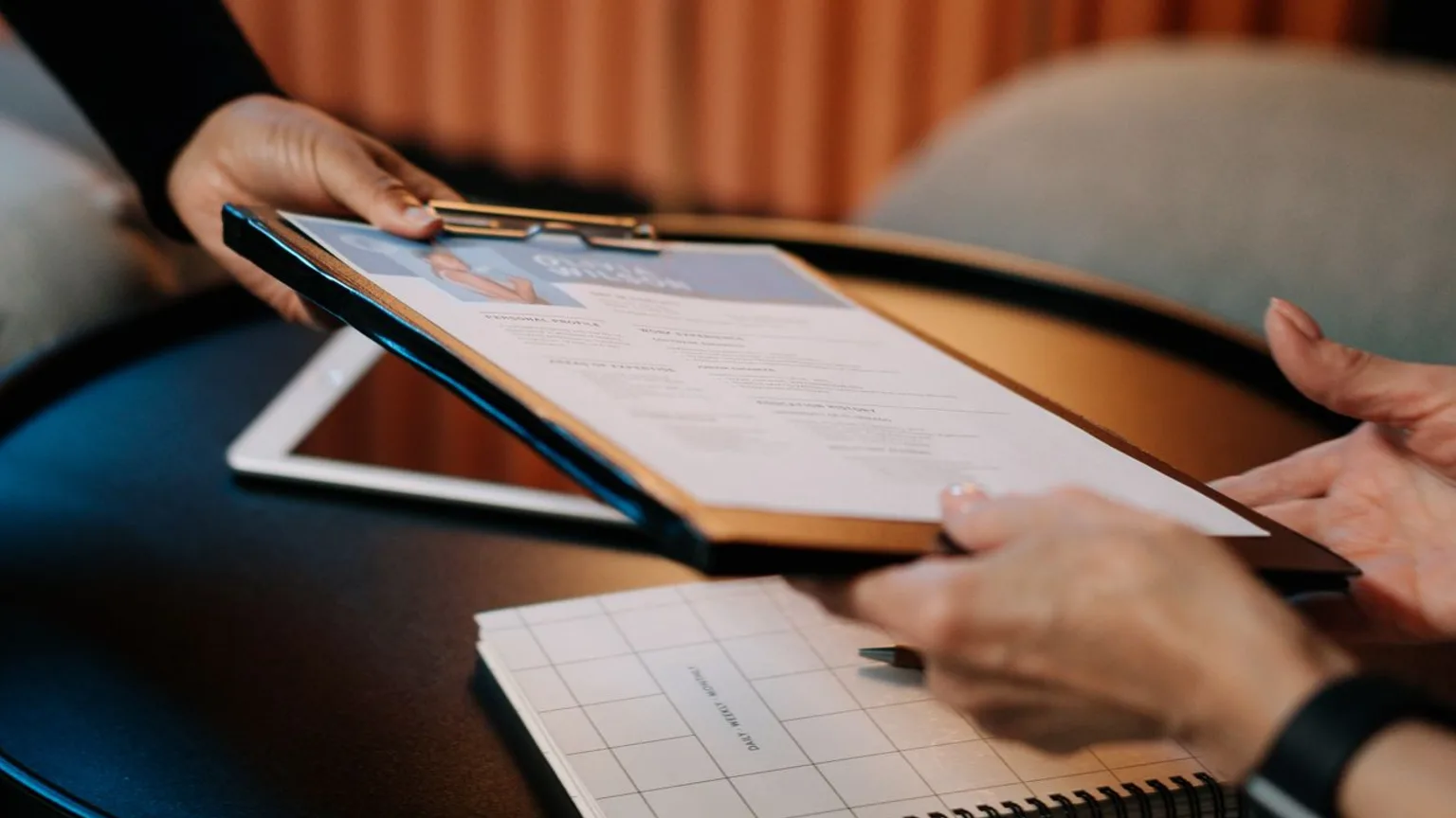 Recruteur examinant le CV d'une candidate sur un porte-documents