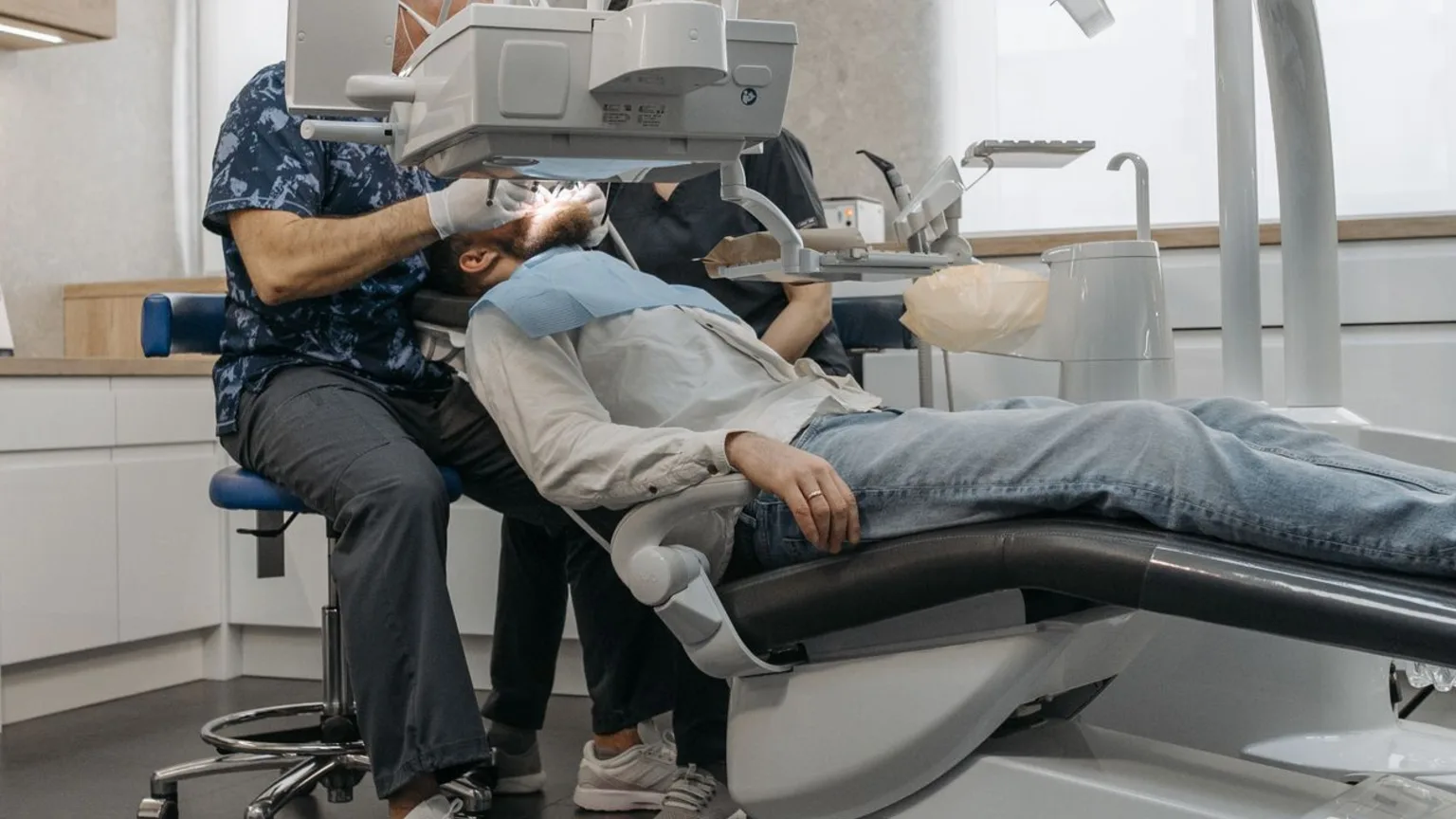 Praticien intervenant au fauteuil dans une salle de soins dentaire