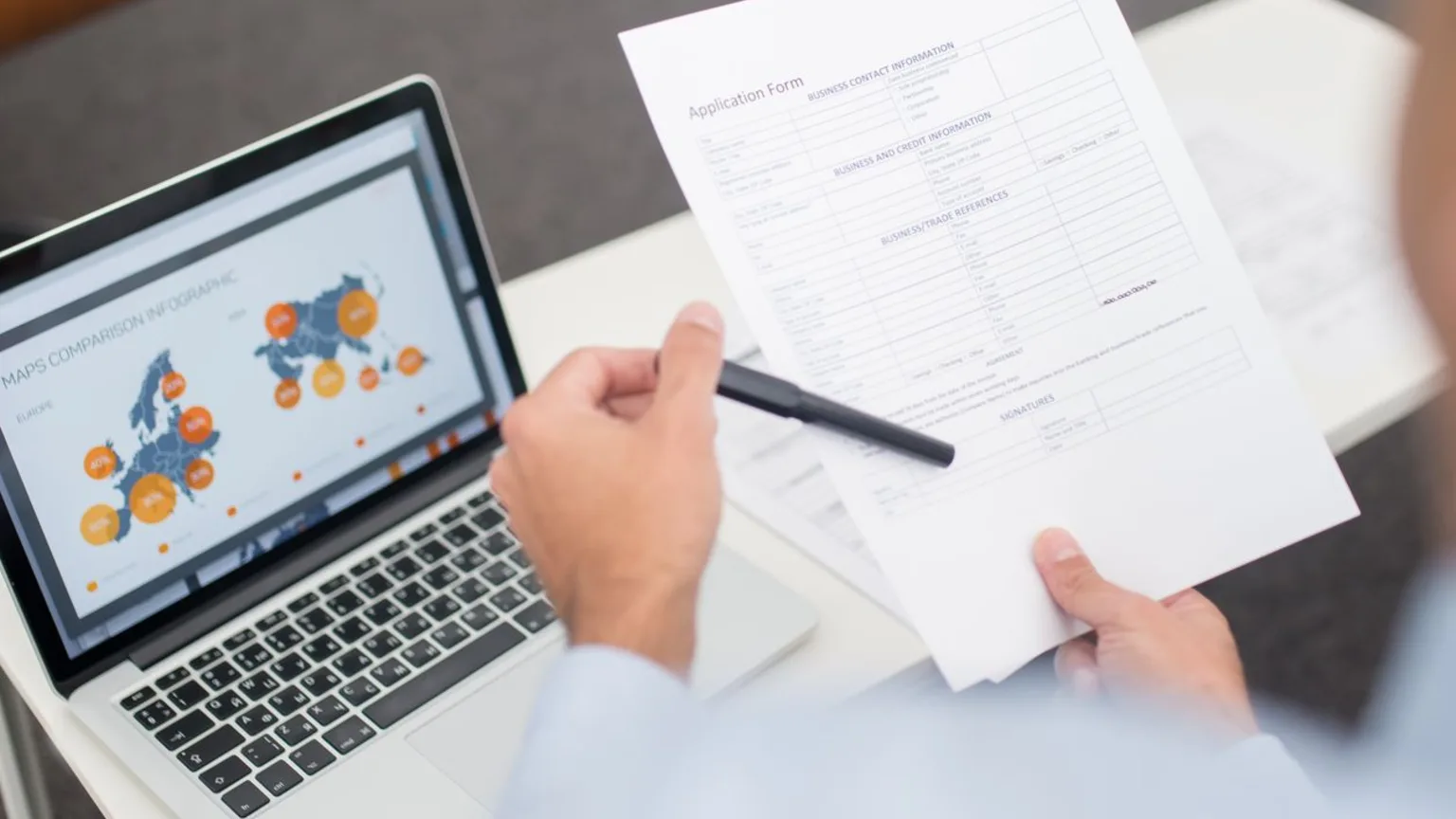 Professionnel vérifiant un document administratif à côté d'un ordinateur portable